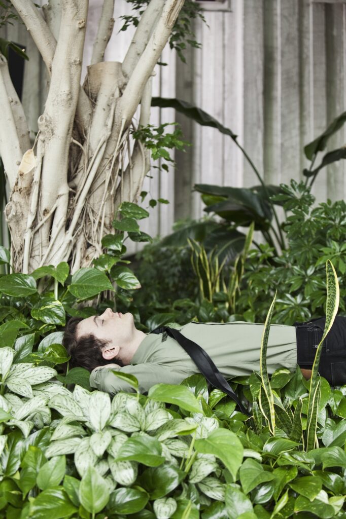 A Caucasian businessman taking a break in a convention center lobby full of indoor plants.